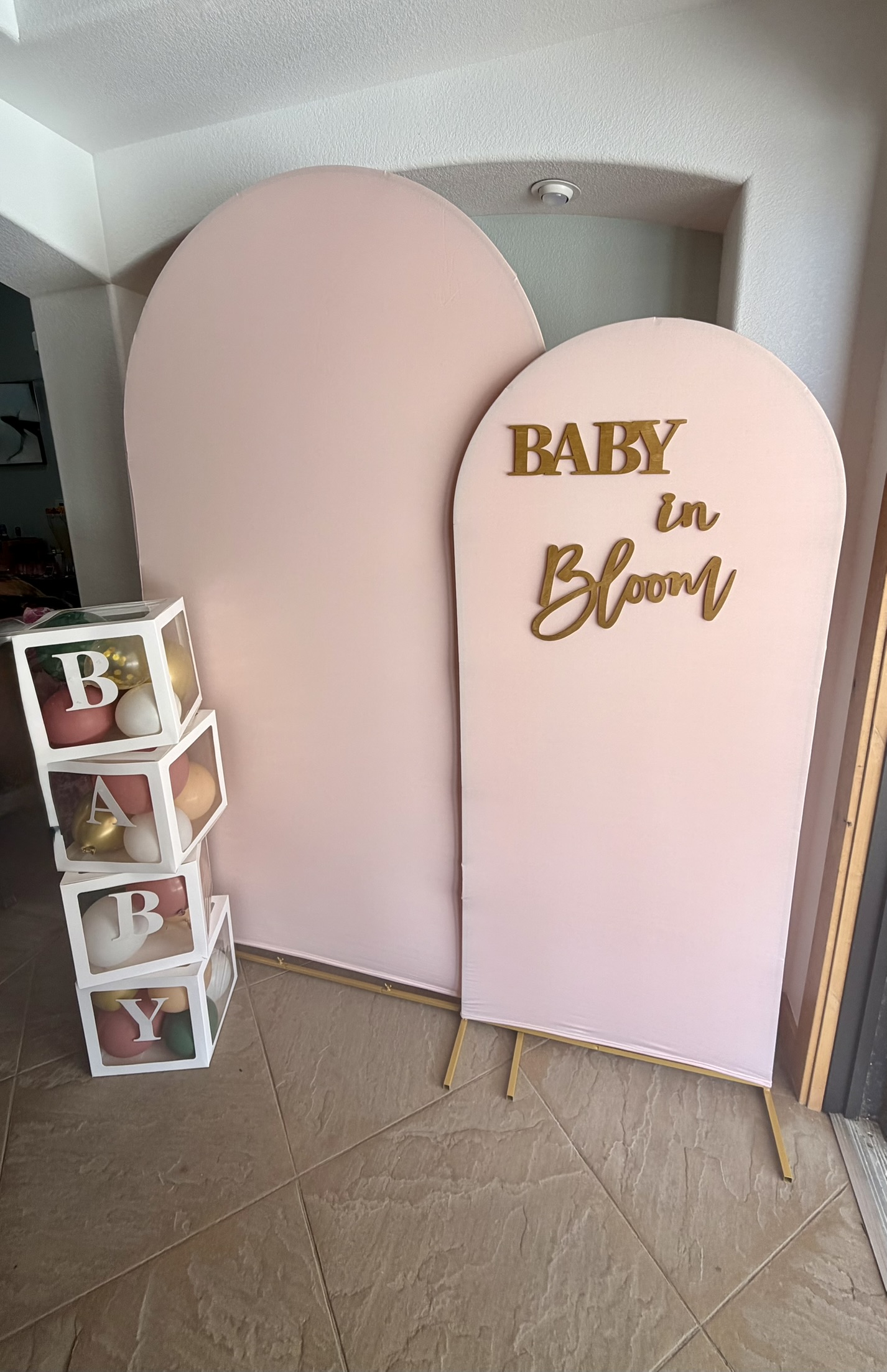 Blush pink arch backdrops with gold Baby in Bloom lettering and balloon-filled baby blocks
