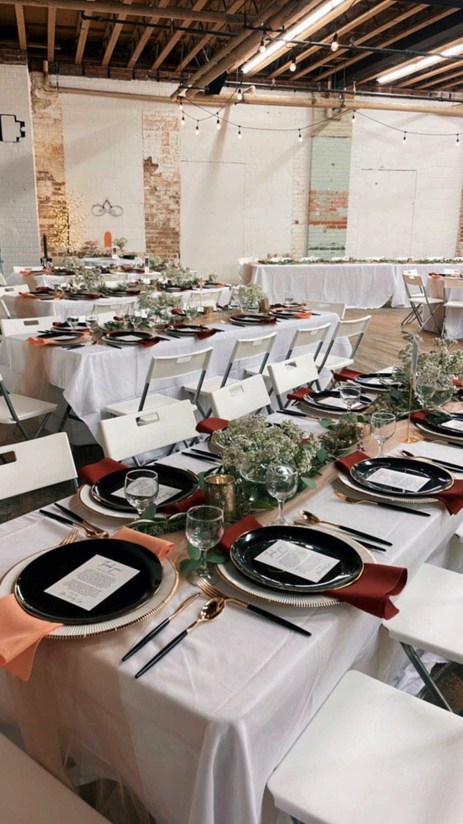 Wedding reception tables beneath string lights and exposed timber beams